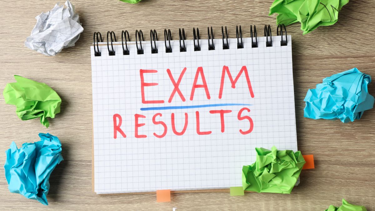 The words 'exam results' written in a note pad, with screwed up pieces of paper on the desk around the notepad.