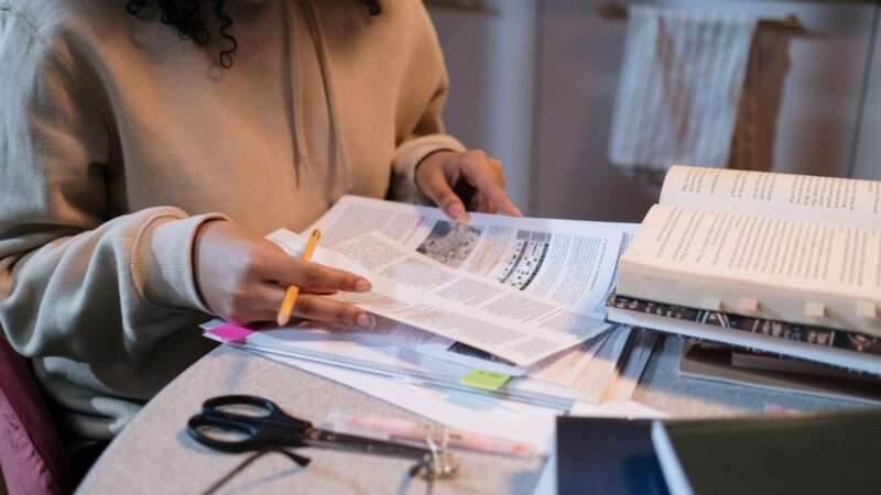 Young person sat at her desk at home studying, looking through a form.