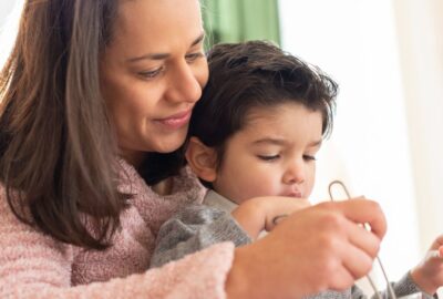 A young child and his foster carer. Foster carer is helping the young boy at the table