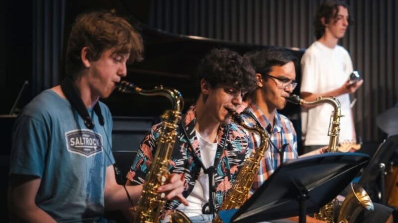 Three young people playing saxophone on stage