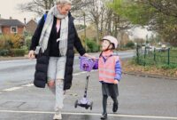 Young girl in hi-vis crossing the road with her mum