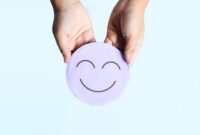 An image that shows a two hands holding a round disk, and the disk has a smiley face on it