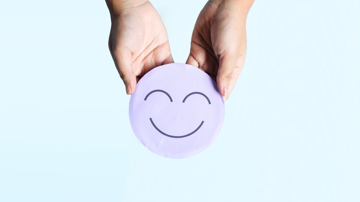 An image that shows a two hands holding a round disk, and the disk has a smiley face on it