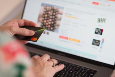 A person looking at a website on his laptop, and he is holding his credit card, as if to make a payment