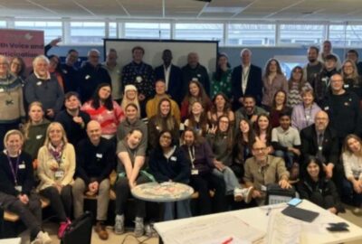 Attendees at the Youth Voice Saturday. A large group of attendees stood and sat facing the camera smiling