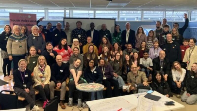 Attendees at the Youth Voice Saturday. A large group of attendees stood and sat facing the camera smiling