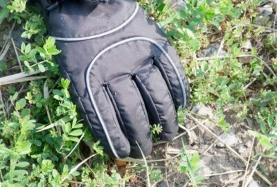 a weedy pavement, with a glove hand clearing the weeds