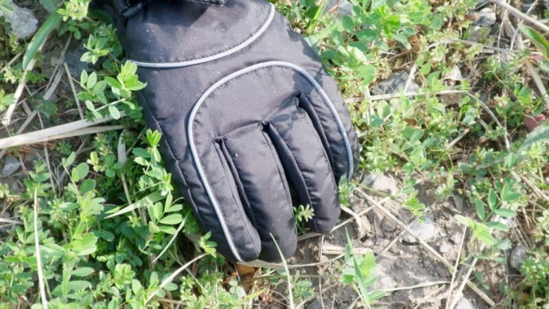 a weedy pavement, with a glove hand clearing the weeds