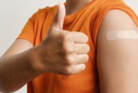 A man holding his thumb up. He has a plaster on his upper arm where he has had the flu jab