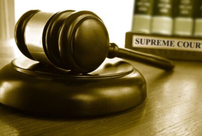 Courtroom gavel with law books and plaque engraved with words 'supreme court'