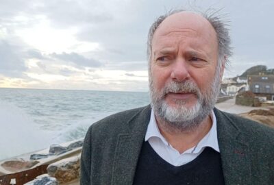 Councillor Julian Brazil, Leader of Devon County Council stood at Torcross with the sea crashing up at the sea wall, following Storm Ingrid