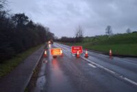 A road closed due to localised flooding. Road signs across the road warning of the closure