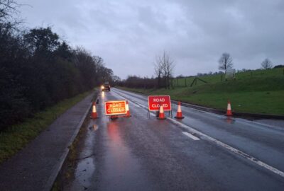 A road closed due to localised flooding. Road signs across the road warning of the closure