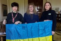 Olya and Oksana, stood with the Chair of Devon County Council, Councillor Caroline Leaver, holding the Ukrainian flag