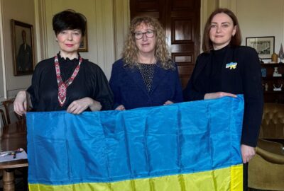 Olya and Oksana, stood with the Chair of Devon County Council, Councillor Caroline Leaver, holding the Ukrainian flag