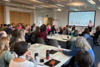 A group of people sat around tables at a conference