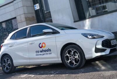 A Co Wheels car parked by the side of an urban road