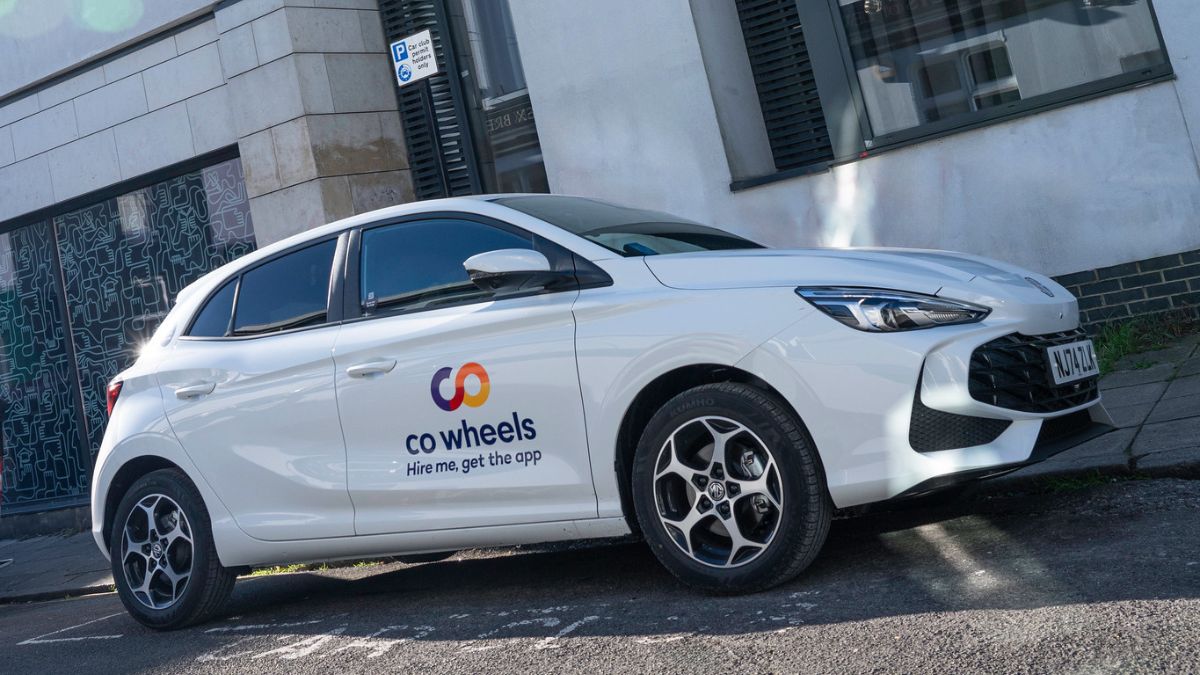 A Co Wheels car parked by the side of an urban road