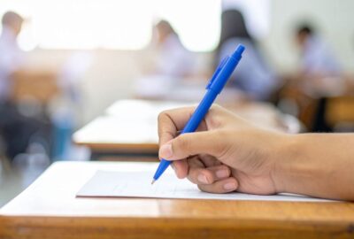 Pupils sitting exams. Picture shows a hand holding a pen, poised over their exam sheet