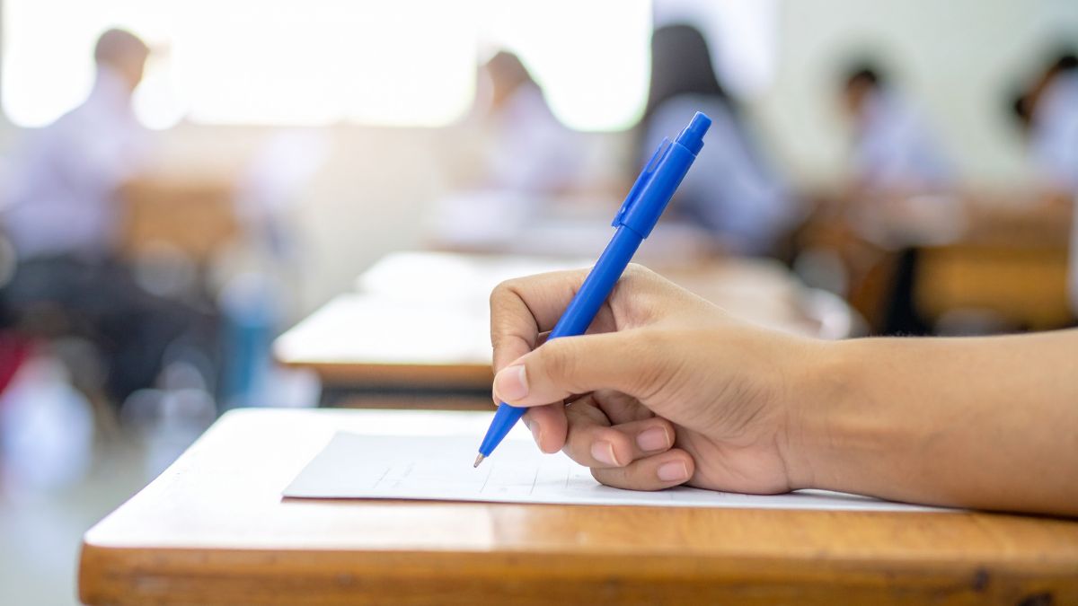 Pupils sitting exams. Picture shows a hand holding a pen, poised over their exam sheet