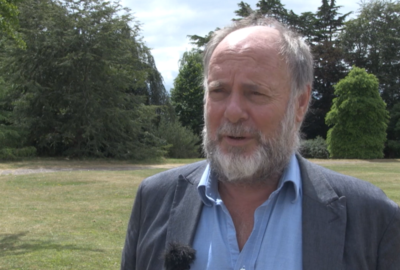 Councillor Julian Brazil, Leader of Devon County Council, outdoors in a field with trees behind.