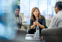 Three people having a meeting around a low table.