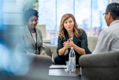 Three people having a meeting around a low table.