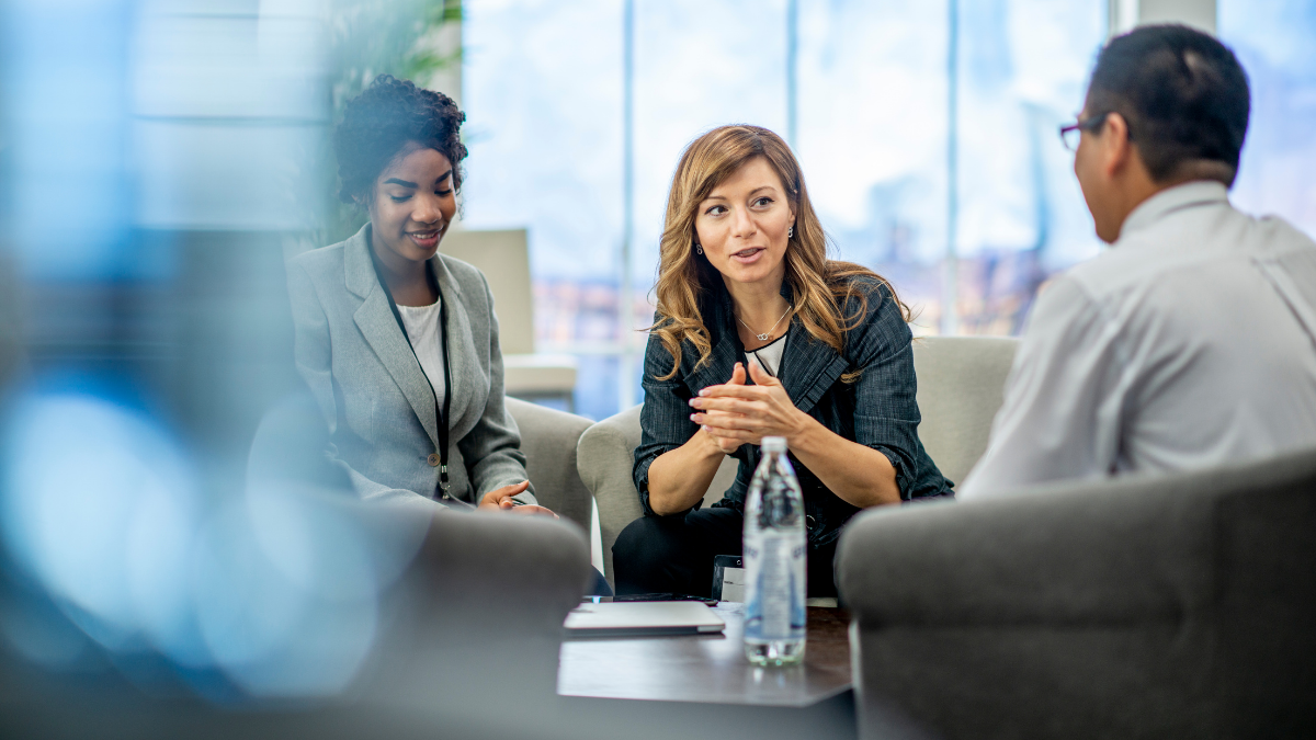 Three people having a meeting around a low table.