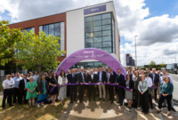 People gather outside Vistry's new office building at Skypark, Exeter, for an opening ceremony beneath a Vistry-branded arch.