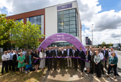 People gather outside Vistry's new office building at Skypark, Exeter, for an opening ceremony beneath a Vistry-branded arch.