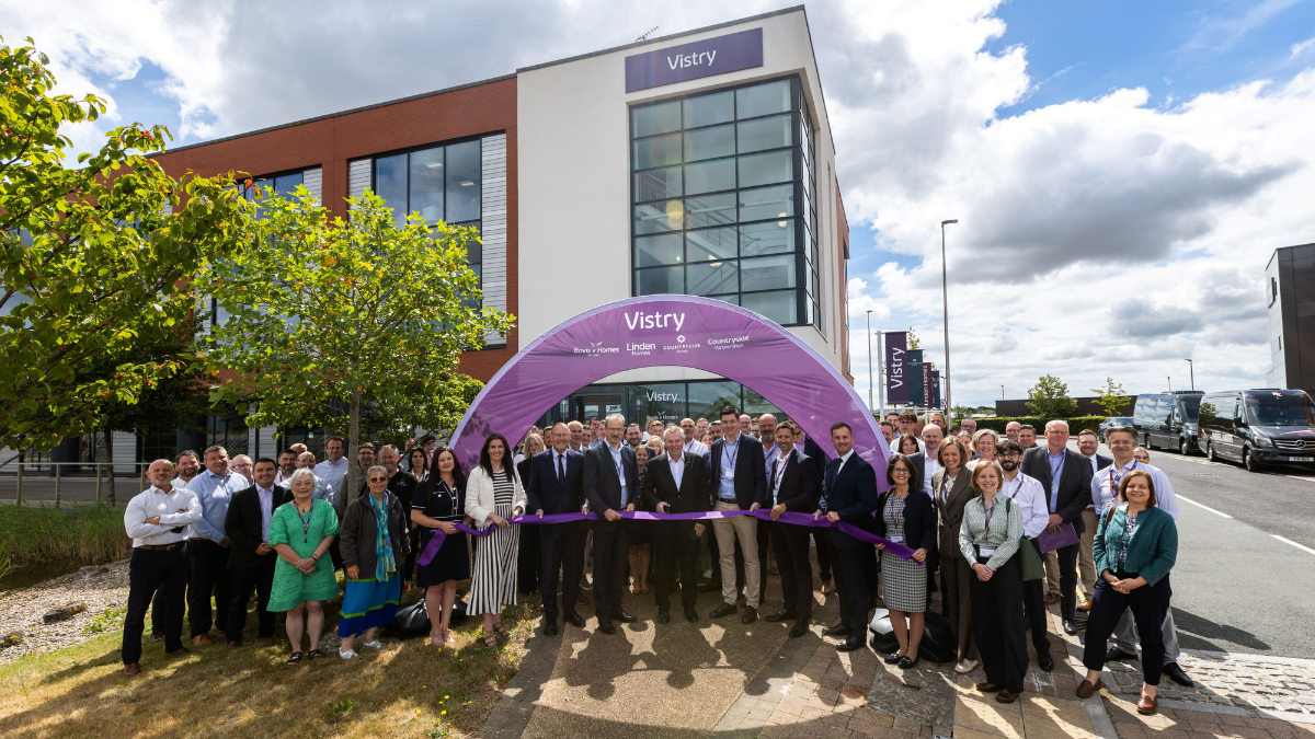 People gather outside Vistry's new office building at Skypark, Exeter, for an opening ceremony beneath a Vistry-branded arch.
