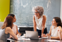 A group of people holding a group meeting in front of a board with maths on it