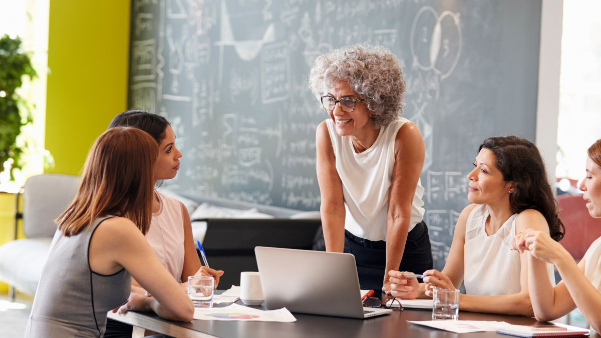 A group of people holding a group meeting in front of a board with maths on it