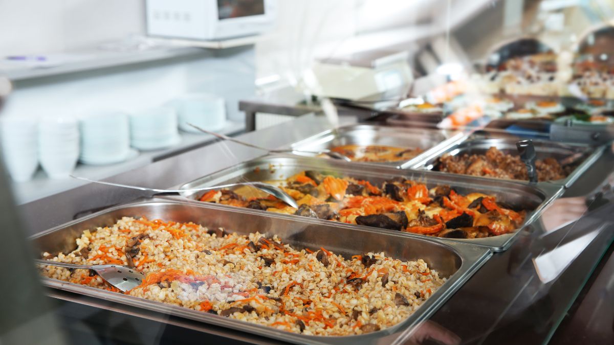 School dinners, in large catering trays, containing pasta and other foods.