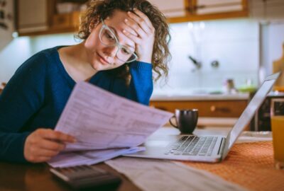 A lady, holding her head in her hands, looking at a household bill.