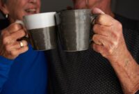Couple having a cup of tea together, touching their two mugs together.