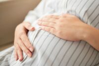 A pregnant woman sat with her hands on her stomach