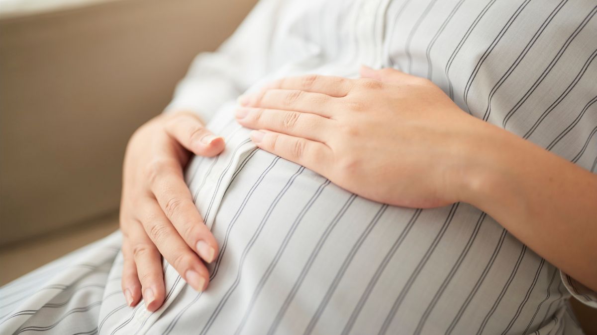 A pregnant woman sat with her hands on her stomach