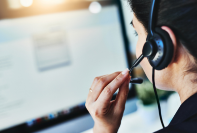 Someone adjusting the mic of their headset whilst looking at a screen.