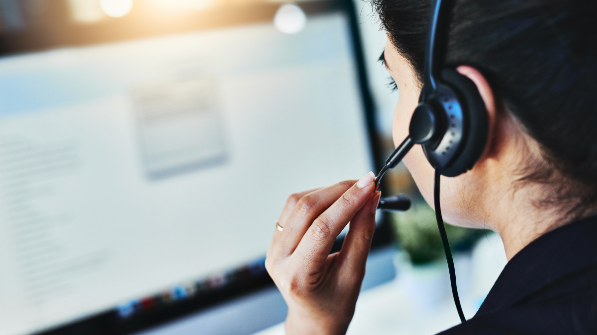 Someone adjusting the mic of their headset whilst looking at a screen.