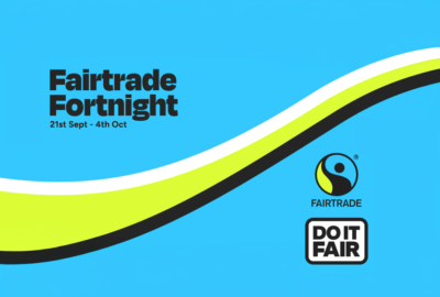 Fairtrade Fortnight promotional graphic with a bright blue background and curved white, lime green and black bands sweeping across the image. Text reads “Fairtrade Fortnight, 21st Sept – 4th Oct”. The Fairtrade logo and “Do It Fair” campaign logo appear on the right-hand side.