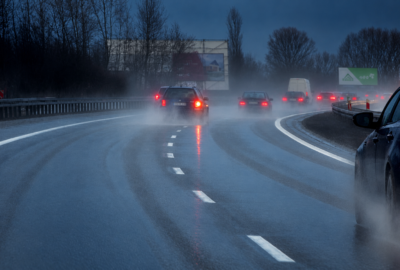 Cars driving through rain at dusk on a wet road