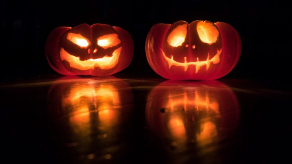 Two glowing carved Halloween pumpkins against a dark background.