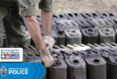 A person filling up jerry cans with fuel, with gloved hands and sleeves rolled up