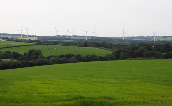 Denbrook windfarm. The turbines are situated in the countryside with fields and trees in the foreground.
