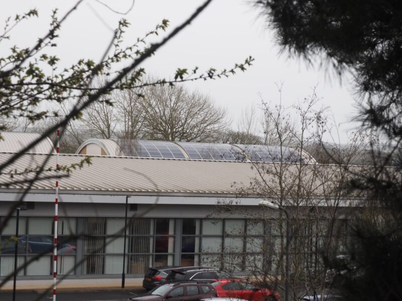 A large building with rooftop solar PV arrays at Great Moor House (Exeter Community Energy).