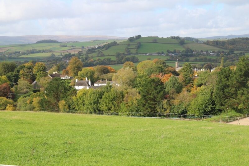 Mid Dart Valley and Slopes - View from public footpath east of Broadhempston towards Dartmoor in the far distance. GPS Coordinates 280999 65895. Hill of green fields, bordered by hedges, with small villages and patches of woodland. Dartmoor hills in the distance.