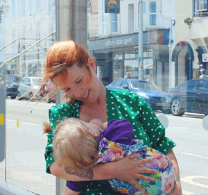 Mother breastfeeding her daughter waiting for the bus