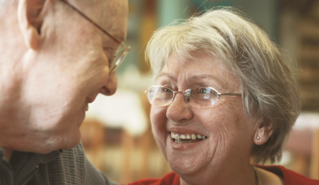 An older lady and man looking at each other and smiling