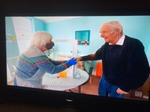 Two peopel holding hands in care home.